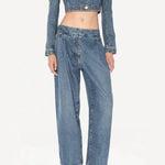 Front view of bleu delave pleated pants on model wearing crop jacket and boots, against a white background.