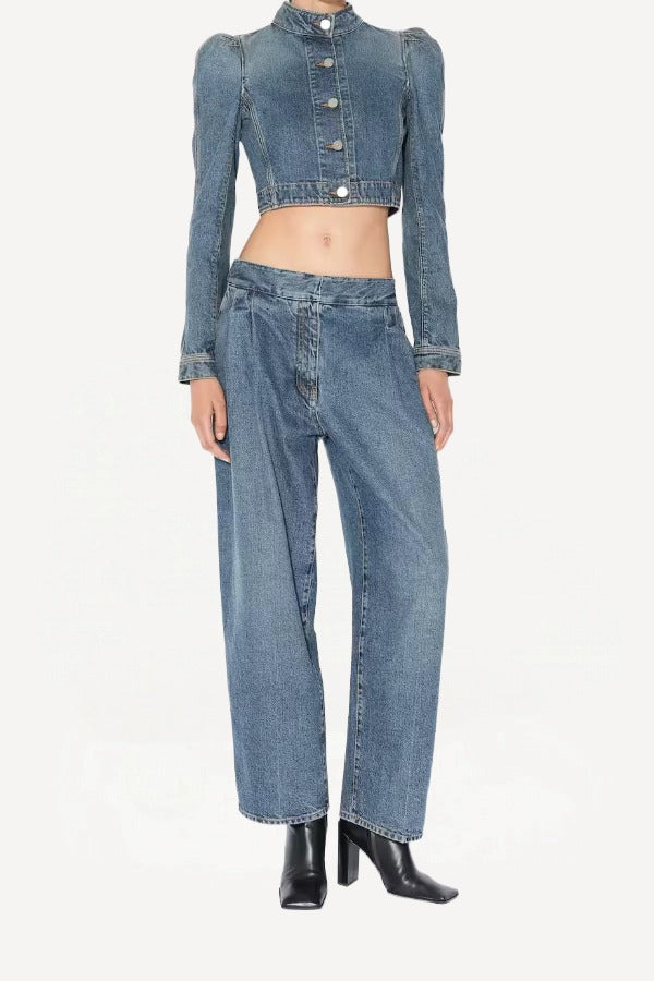 Front view of bleu delave pleated pants on model wearing crop jacket and boots, against a white background.