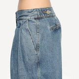 Side closeup view of bleu delave pleated pants on model wearing crop jacket, against a white background.