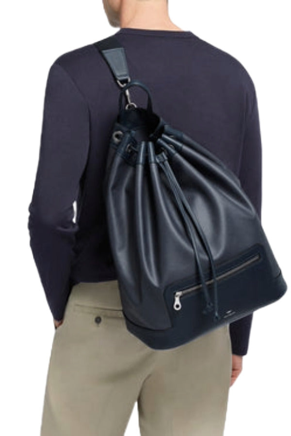 Front view of navy shoulder bag on model wearing khaki trousers and navy shirt on white background.