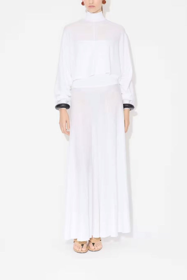 Front view of white batwing jumper on model wearing white maxi dress underneath, against a white background.