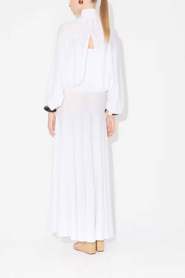 Back view of white batwing jumper on model wearing white maxi dress underneath, against a white background.