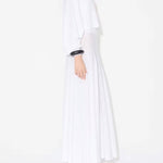 Side view of white batwing jumper on model wearing white maxi dress underneath, against a white background.