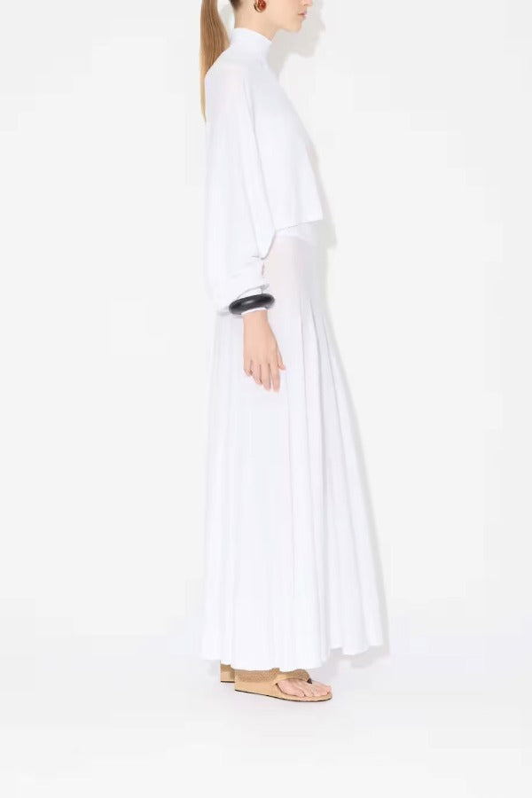 Side view of white batwing jumper on model wearing white maxi dress underneath, against a white background.