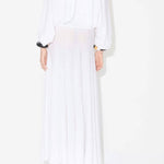 Back view of white linen maxi dress on model wearing white pullover and natural wedge sandals, against white background.
