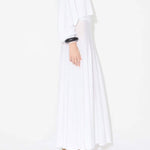 Side view of white linen maxi dress on model wearing white pullover and natural wedges, against white background.