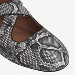 Closeup view of white/black criss cross ballet flats on white background, with no model shown.