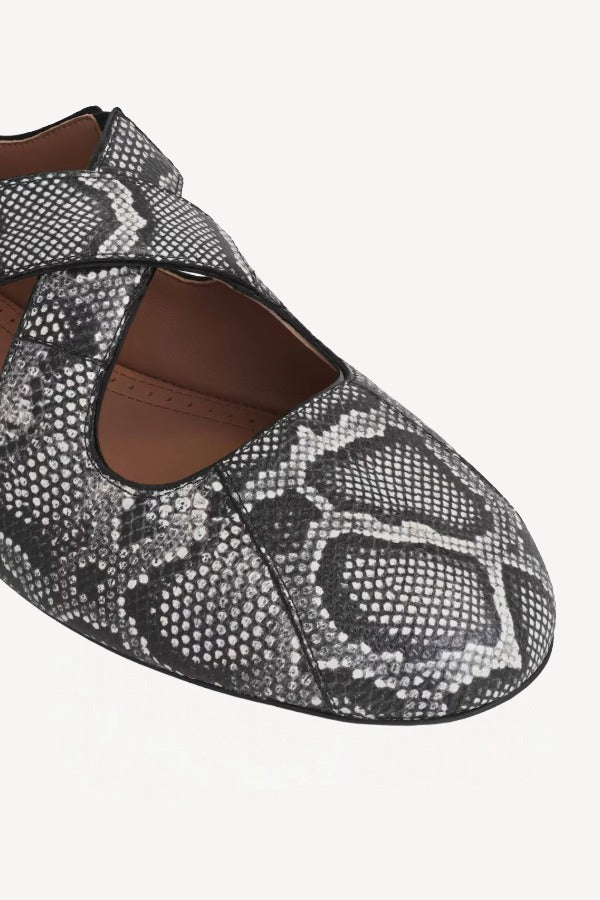 Closeup view of white/black criss cross ballet flats on white background, with no model shown.