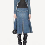 Front view of denim cropped jacket on model wearing black bodysuit, denim skirt and boots, against a white background.
