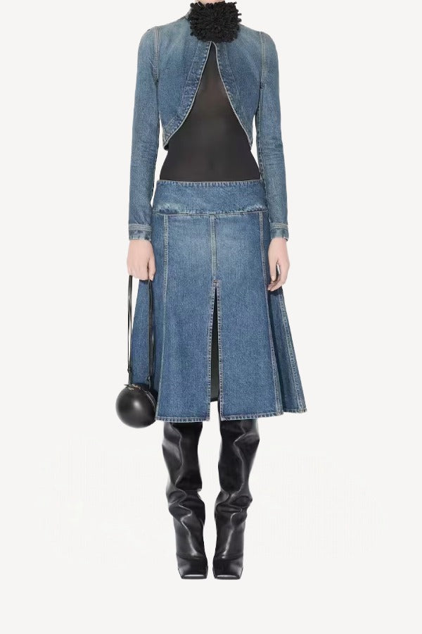 Front view of denim cropped jacket on model wearing black bodysuit, denim skirt and boots, against a white background.
