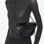 Alternate front view of noir hip east west bag on model wearing black top and pants, against a white background.