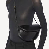 Alternate front view of noir hip east west bag on model wearing black top and pants, against a white background.