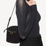 Front view of noir la canette small bag on model wearing black top and pants, against a white background.