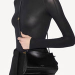 Front view of noir le click small square bag on model wearing black top and pants, against a white background.