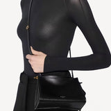Front view of noir le click small square bag on model wearing black top and pants, against a white background.