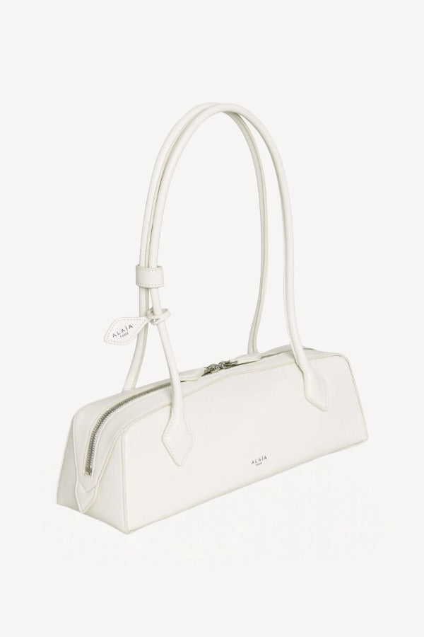 Side slanted view of ivoire le teckel medium bag on white background, with no model shown.