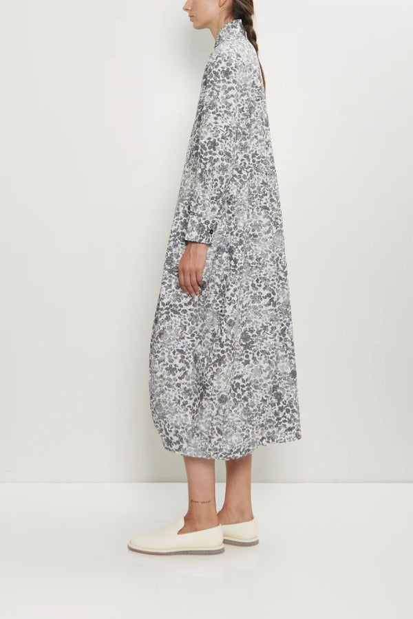 Side view of bright flower letty dress on model wearing white loafers, against a white background.