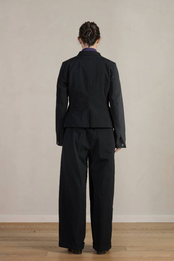 Back view of pinstripe caryl jacket on model wearing black trousers, against a white background.