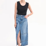 Front view of indigo denim skirt on model wearing black tank top and black sandals, against white background.