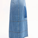 Back view of indigo denim skirt on model wearing black tank top and black sandals, against a white background.