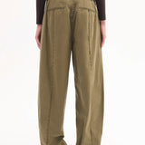 Back view of olive drop waist pant on model hearing brown long-sleeve shirt and black pointed toe heels