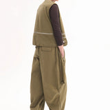 Back view of olive hunters gilet on model wearing brown shirt, olive trousers and brown pointed toe heels, against a white background.
