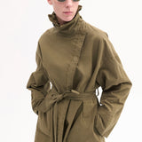 Front closeup view of olive oversized trench coat on model wearing sunglasses, against white background.