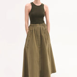 Front view of olive parachute skirt on model wearing dark green tank top and black sandals, against white background.