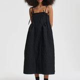 Front view of black ambra dress on model wearing black sneakers, against a white background.