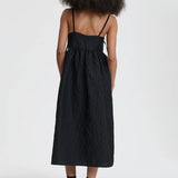 Back view of black ambra dress on model wearing black sneakers, against a white background.