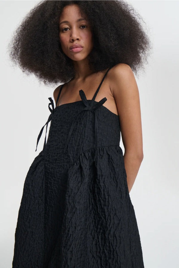 Front closeup view of black ambra dress on model, against a white background.