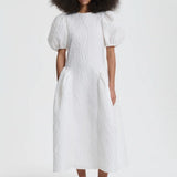 Front view of white bali dress on model wearing black flats, against a white background.