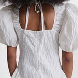 Back closeup view of white bali dress on model, against a white background.