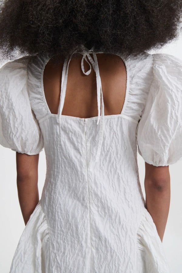 Back closeup view of white bali dress on model, against a white background.