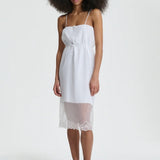 Front view of white barr dress on model wearing black flats, against a white background.