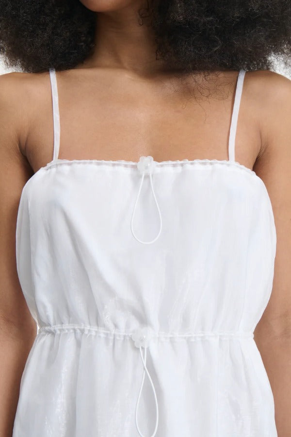 Front closeup view of white barr dress on model, against a white background.