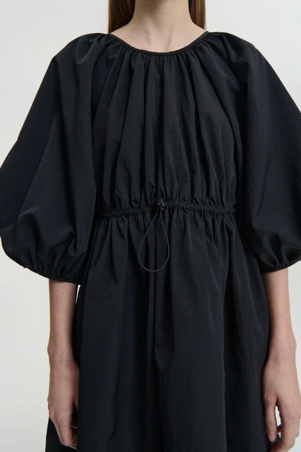 Front closeup of black birgitte dress on model, against a white background.