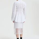 Back view of white braxton shirt on model wearing white slip and black sneakers, against a white background.