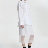Side view of white braxton shirt on model wearing white slip and black sneakers, against a white background.