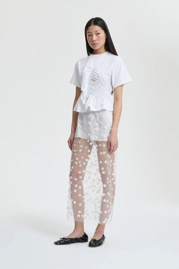 Front view of white gus skirt on model wearing whiter shorts and top with flats, against a white background.