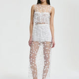 Front view of white utania top on model wearing white shorts and black flats, against a white backgound.