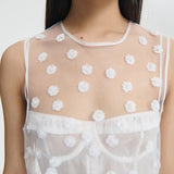 Front closeup view of white utania top on model wearing white brassiere against a white background.