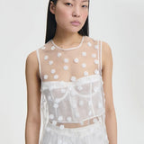 Alternate front view of white utania top on model wearing white brassiere and shorts, against a white background.
