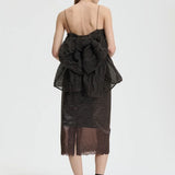 Back view of soil brown veronica top on model wearing brown skirt and sneakers with socks, against a white background.