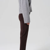 Side view of barrister caia pants on model wearing grey sweater and heels, against a white background.