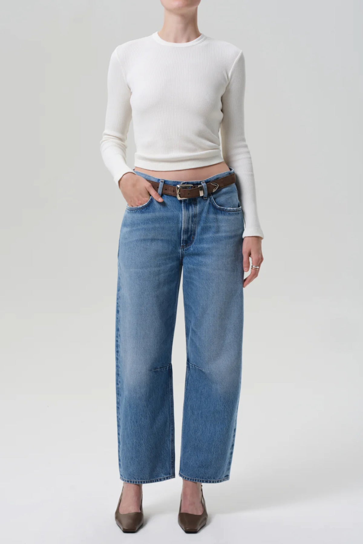 Front view of miro jean in corrin on model wearing a white t-shirt and brown heels, against a white background.