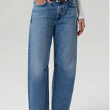 Front slanted view of miro jean in corrin on model wearing white t-shirt and brown heels, against a white background.