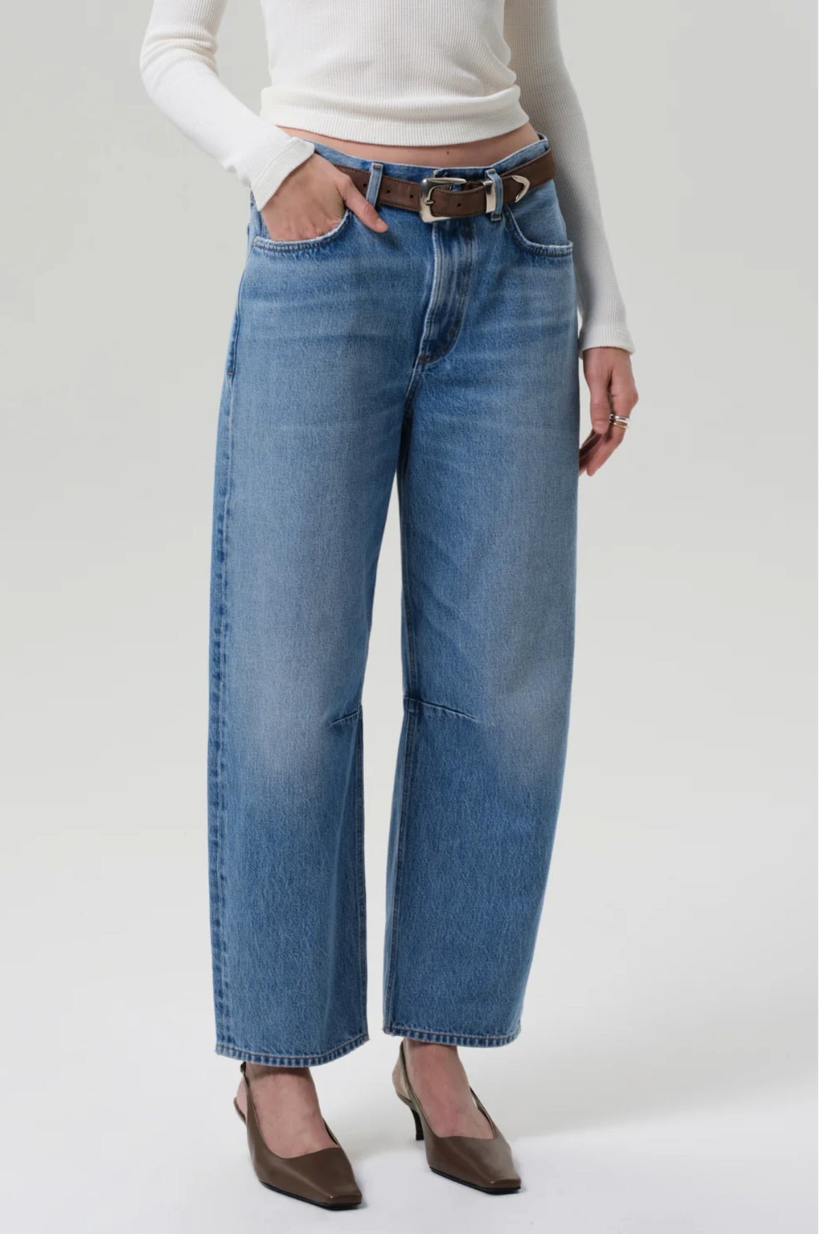 Front slanted view of miro jean in corrin on model wearing white t-shirt and brown heels, against a white background.