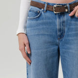 Front closeup of miro jean in corrin on model wearing white t-shirt and brown belt, against a white background.