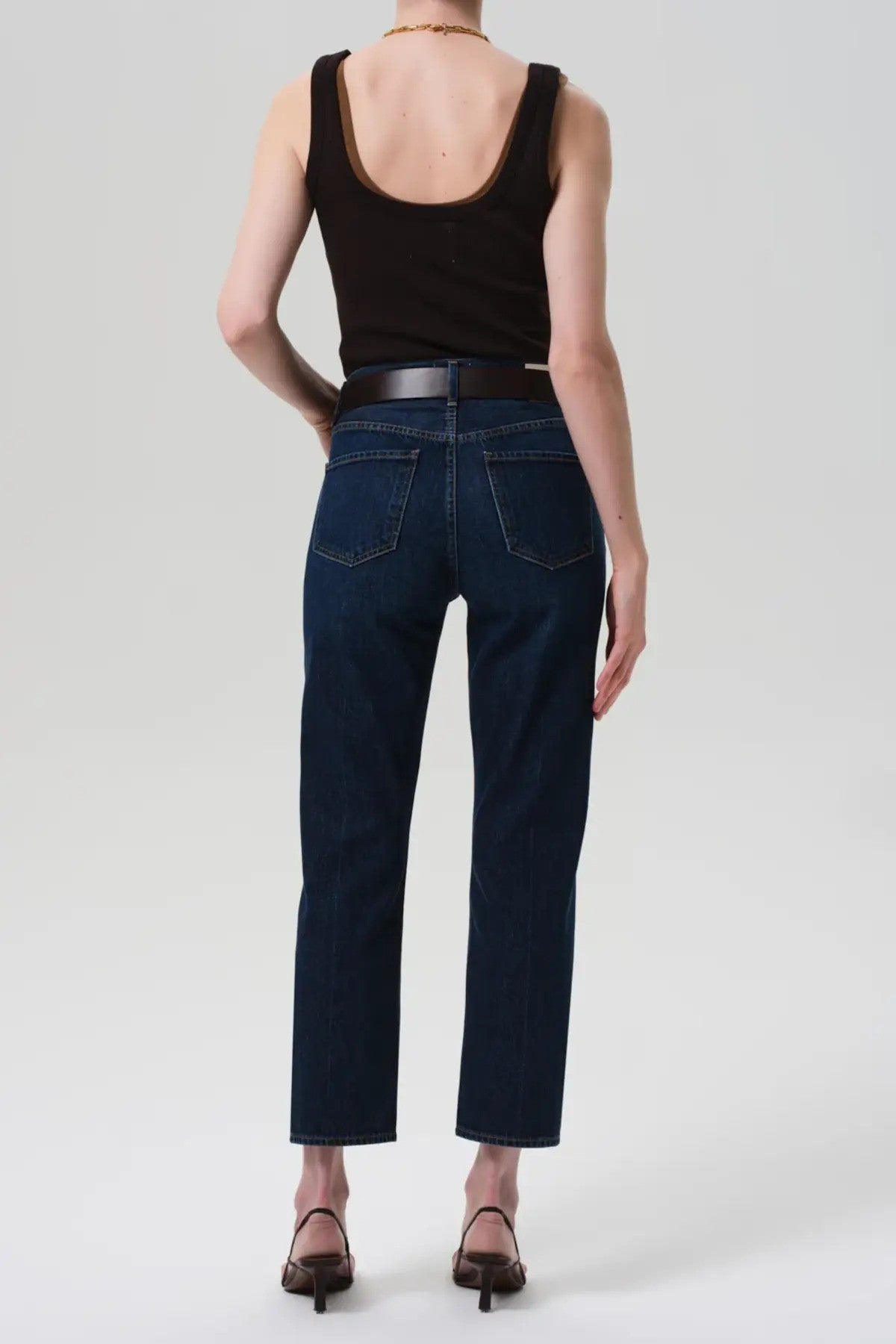 Back view of blaine jean in medina on model wearing black and brown tank tops with black heels, against a white background.